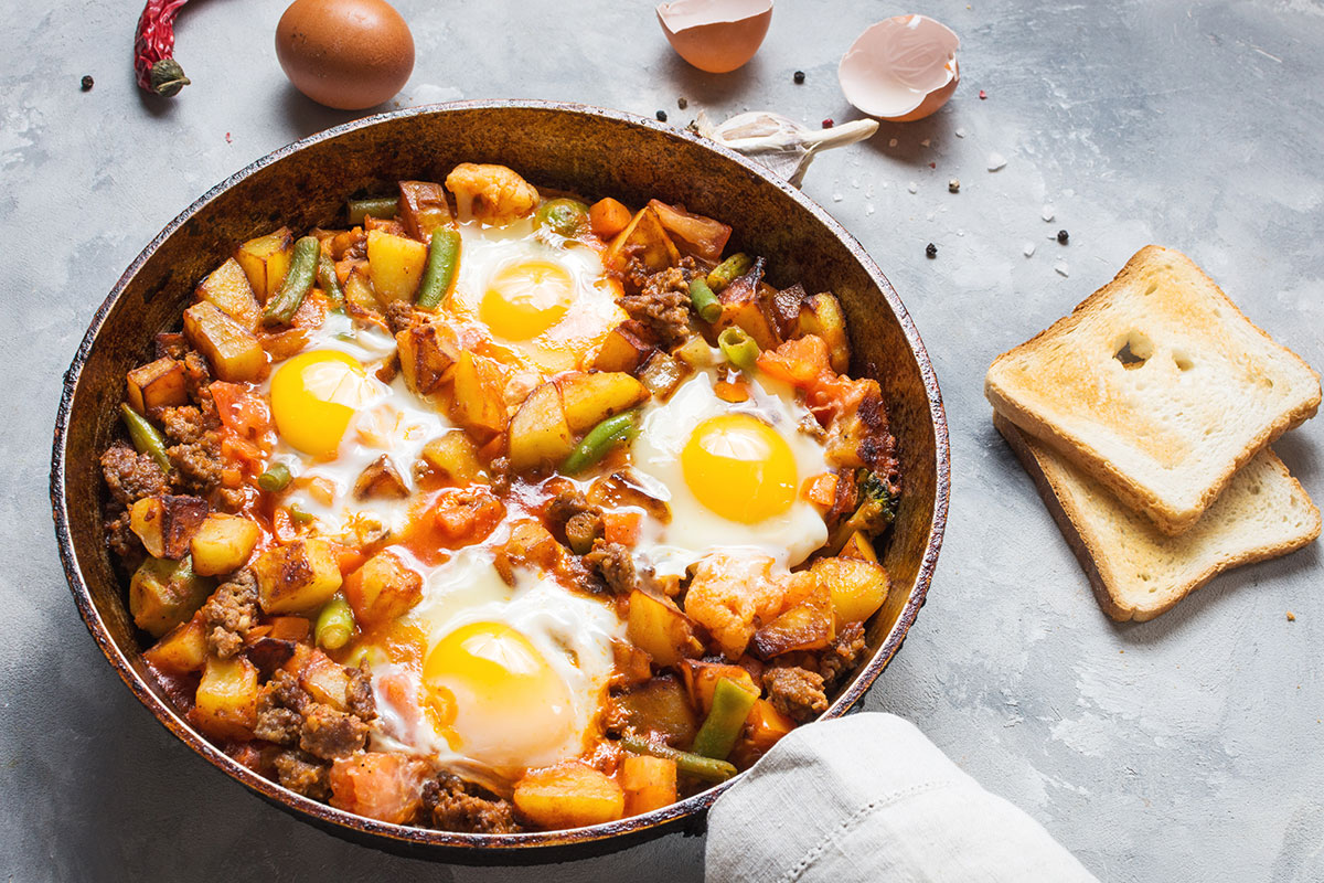 Breakfast hash in a skillet with four eggs